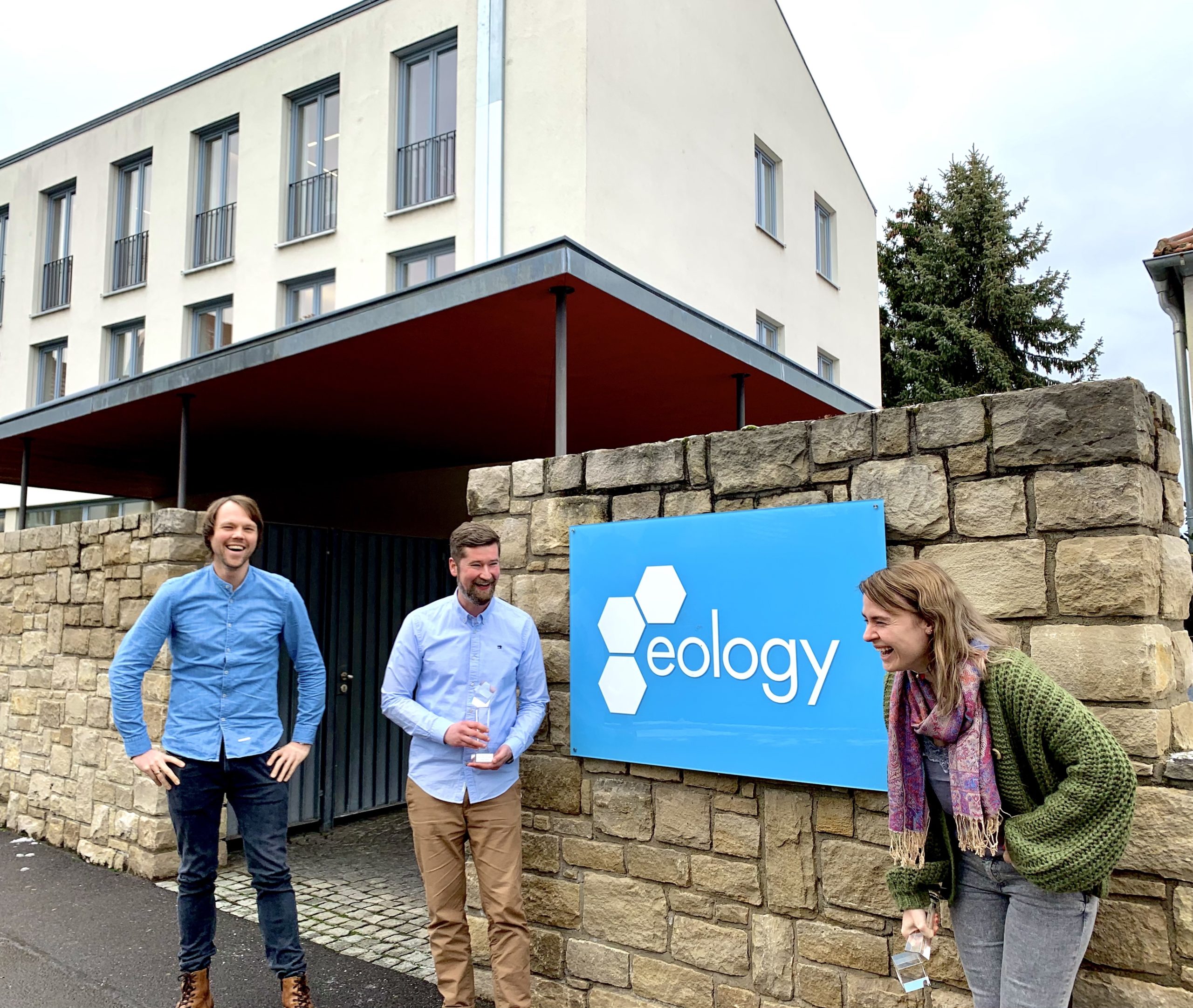 Auf dem Bild zu sehen sind die beiden Geschäftsführer Daniel Unger und Axel Scheuering mit Senior SEO Consultant Lena Kapp vor dem Volkacher Büro der eology GmbH.