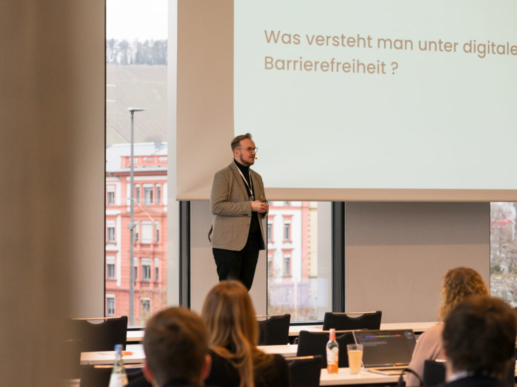 Zu sehen ist Lars Assent, der beim eoSearchSummit 2025 über die Notwendigkeit von Barrierefreiheit im Internet aufklärt.